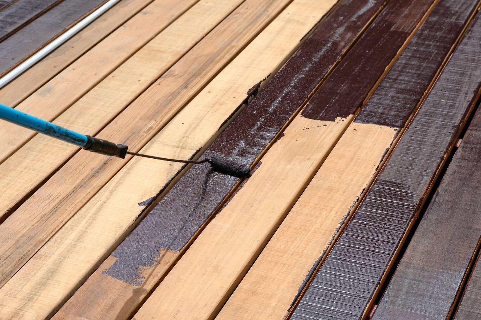 Worker painting with paint roller on wood floor